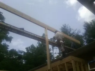 Carpenter setting a ridge beam over a new addition frame — Ice Dam Removal by Roofing Brothers in Mc David