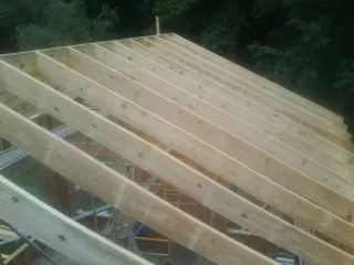 New roof rafters set over an addition before sheathing in Mc David