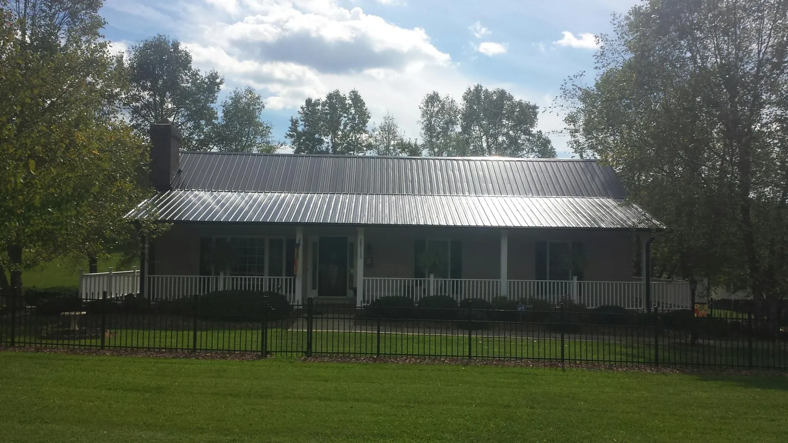 Gray metal roof on a brick ranch with a full width front porch — Gutter Guard Installation work by our crew in Mc David