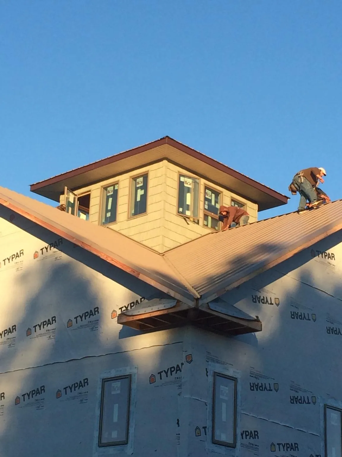 Roofers working around a rooftop cupola on a new metal roof at sunset — Roof Waterproofing in Mc David by Roofing Brothers